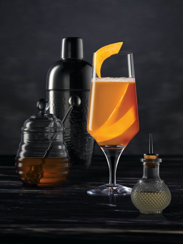 Cocktail mixing tools surrounding a Brown Derby on a dark surface